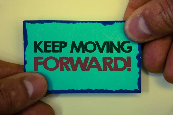 Writing note showing  Keep Moving Forward Motivational Call. Business photo showcasing Optimism Progress Persevere Move Greyish backstage man hand retain blue outskirts page showing words