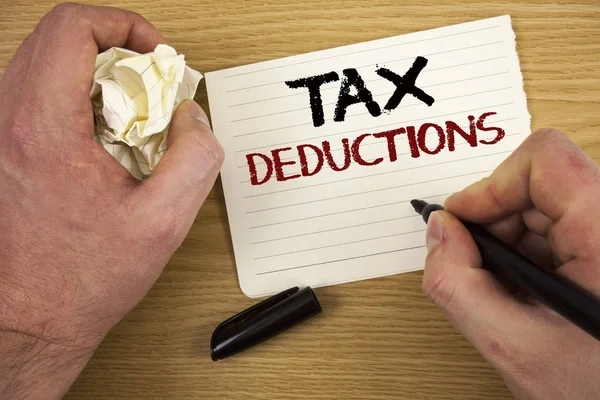 Handwriting text Tax Deductions. Concept meaning Reduction on taxes Investment Savings Money Returns Text two words white paper note black marker hand crumbled paper note