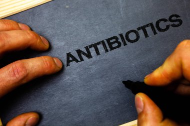 Metin antibiyotik yazılı kelime. Antibakteriyel ilaç dezenfektan aseptik sterilize sıhhi adam için iş kavramı tutun defter Ahşap ahşap arka plan siyah kalemi işaretleri holding