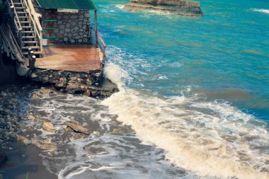 Dalgalar kayalara çökmesini. Okyanus hareketi againts taşlar. Mavi deniz harap bir ev patlatma. Akdeniz Surf smashing wodden merdiven. Sıvı slaming taş Harabeleri.