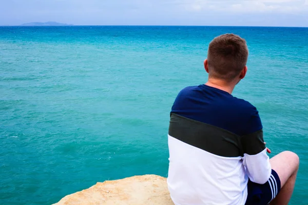 Cliff üzerinde oturan adam. Turist ovelooking deniz. Shoaling dalgalar ve approcahing deniz dibinin. Tropikal hedef rahatlatıcı. Gezi ve açık besleyicisini etkinliği.