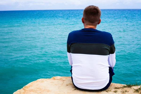 Cliff üzerinde oturan adam. Turist ovelooking deniz. Shoaling dalgalar ve approcahing deniz dibinin. Tropikal hedef rahatlatıcı. Gezi ve açık besleyicisini etkinliği.