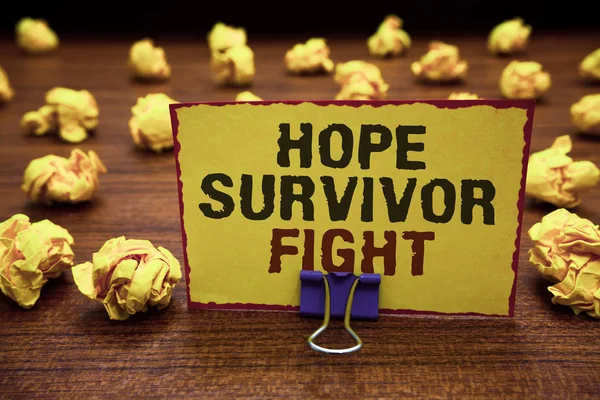 Handwriting text writing Hope Survivor Fight. Concept meaning stand against your illness be fighter stick to dreams Yellow sticky card clipped text notice crumpled paper balls wood table