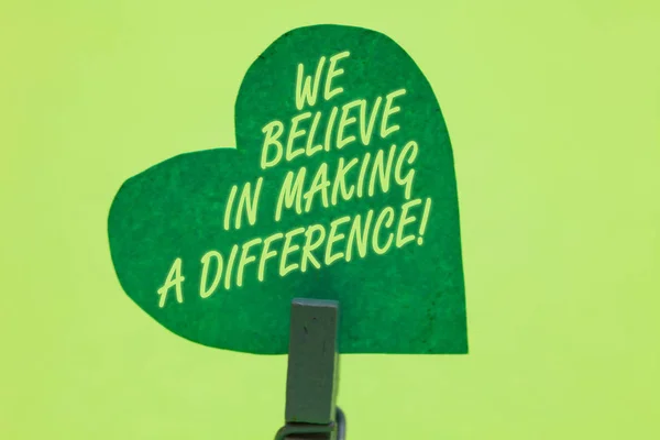 Conceptual hand writing showing We Believe In Making A Difference. Business photo showcasing self-confidence that can be unique Clothespin holding green paper heart romantic message ideas