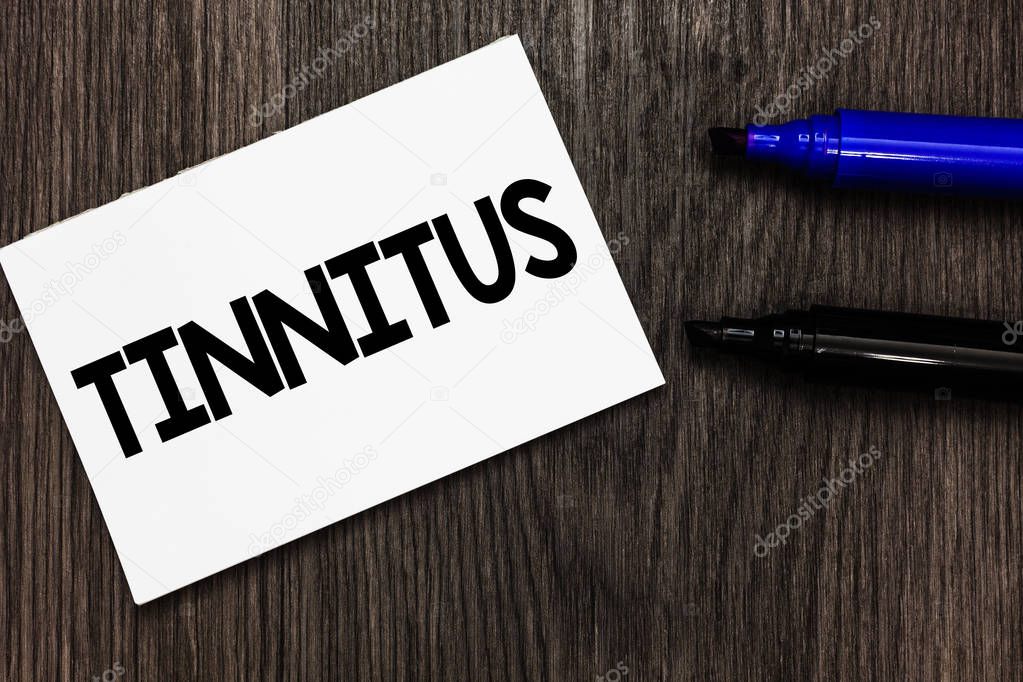 Text sign showing Tinnitus. Conceptual photo A ringing or music and similar sensation of sound in ears Important idea ideas notebook marker markers wooden background reminder