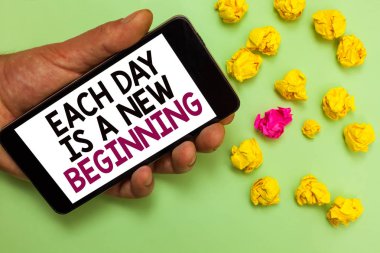 Word writing text Each Day Is A New Beginning. Business concept for Every morning you can start again Inspiration Man holding cell phone white screen looking messages crumpled papers clipart