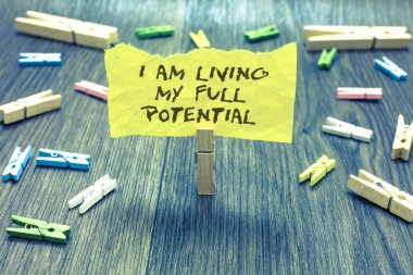 Handwriting text I Am Living My Full Potential. Concept meaning Embracing opportunities using skills abilities Paperclip hold written torn page many clips laid on bluish wooden floor clipart