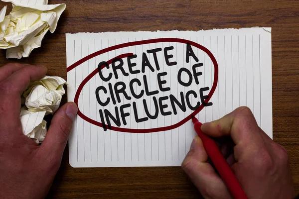 Text sign showing Create A Circle Of Influence. Conceptual photo Be an influencer leader motivate other people Hand hold paper lob and red pen red circled black words on white paper