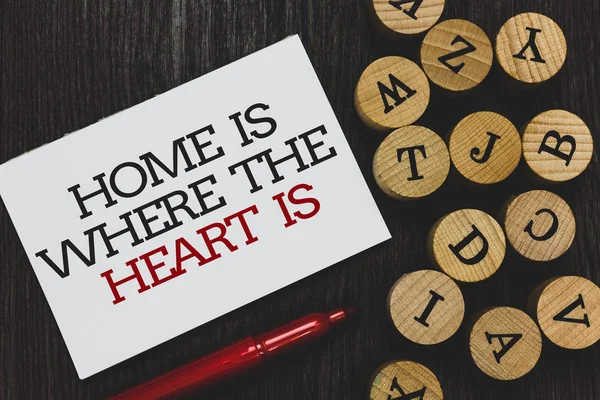 显示主页的文本符号是当心脏是 概念照片你的房子是你觉得舒适和快乐书面纸红色标记旁边圆木制字母表在木头底座上 — 图库照片