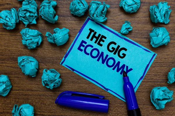 Conceptual hand writing showing The Gig Economy. Business photo showcasing Market of Short-term contracts freelance work temporary written blue letters on page blue marker and paper lumps