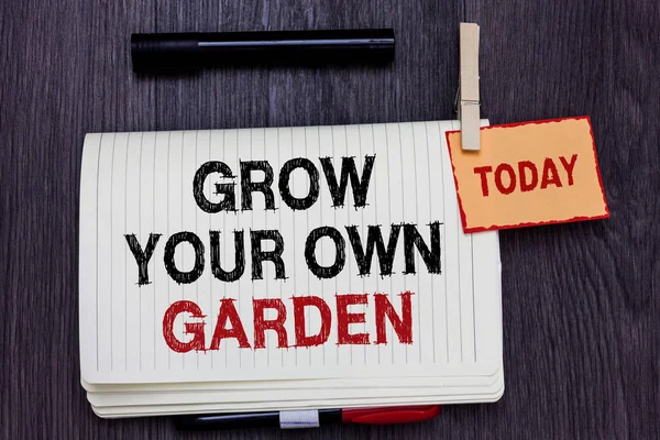 Handwriting text writing Grow Your Own Garden. Concept meaning Organic Gardening collect personal vegetables fruits Written paper on wooden desk paper clip grip note with red words black pen