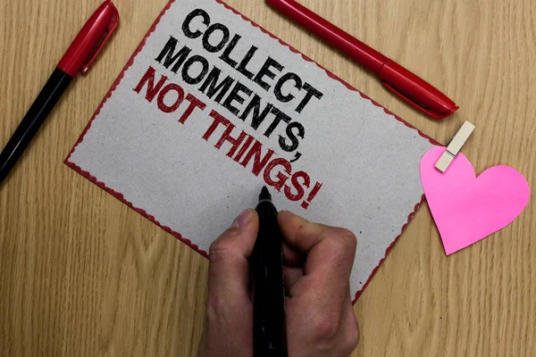 Text sign showing Collect Moments, Not Things. Conceptual photo Happiness philosophy enjoy simple life facts Written sticky note clip pinch heart hand hold marker red pen on wooden desk