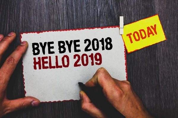 Handwriting text writing Bye Bye 2018 Hello 2019. Concept meaning Starting new year Motivational message 2018 is over Hand grip black marker writing text paperclip stick written page woody deck