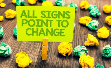 Handwriting text All Signs Point To Change. Concept meaning Necessity of doing things differently new vision Paperclip retain written words yellow paper paper lobs laid on wooden floor clipart