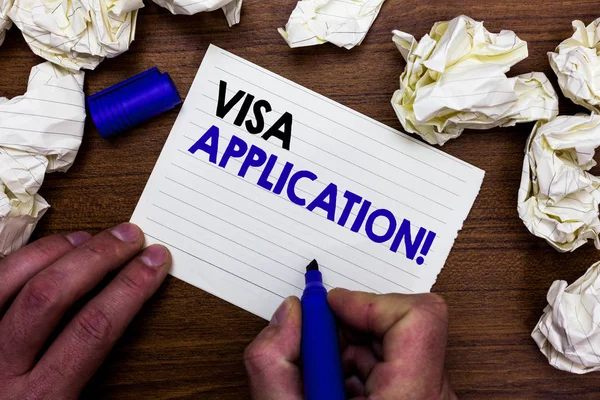 Writing note showing Visa Application. Business photo showcasing Form to ask permission travel or live in another country Hand holding marker write words paper lob scatter around woody desk