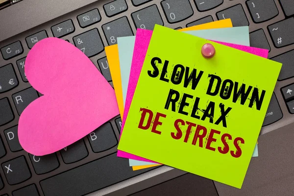 Text sign showing Slow Down Relax De Stress. Conceptual photo Have a break reduce stress levels rest calm Bright colorful written papers pinch by pin pink heart on computer keyboard