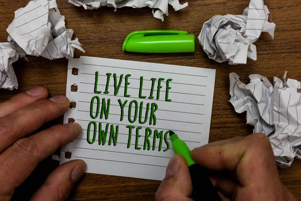 Word writing text Live Life On Your Own Terms. Business concept for Give yourself guidelines for a good living Hand hold green pen and words on white page paper lobs around on wooden desk