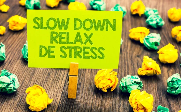 Handwriting text Slow Down Relax De Stress. Concept meaning Have a break reduce stress levels rest calm Paperclip retain written words yellow paper paper lobs laid on wooden floor