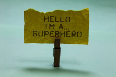 Text sign showing Hello I am A ... Superhero. Conceptual photo Special powers Cartoon character Customs strenght Paperclip hold torn yellow page written brown words sky blue background clipart