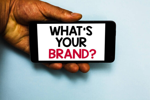 Текст почерка Что такое Ваш бренд вопрос. Понятие, означающее Определение индивидуального товарного знака Идентифицировать компанию Человеческая рука держать мобильный телефон с некоторыми черными и красными буквами цвета
