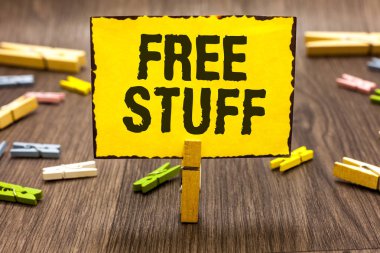 Text sign showing Free Stuff. Conceptual photo Any thing that you can have in a store that is not being paid Clothespin holding yellow paper note several clothespins wooden floor clipart