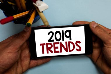 Kavramsal el 2019 Trendler gösterilen yazma. Kısa bir süre geçerli yıl adam holding cep telefonu mesajları apps seyir için ünlü iş fotoğraf vitrine şeyler işaretleri Kupası
