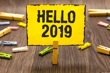 Merhaba 2019 gösterilen metin işareti. Kavramsal fotoğraf bir büyüklük önümüzdeki yılbaşı için olmasını ümit sarı kağıt tutan Clothespin Not birkaç clothespins ahşap zemin