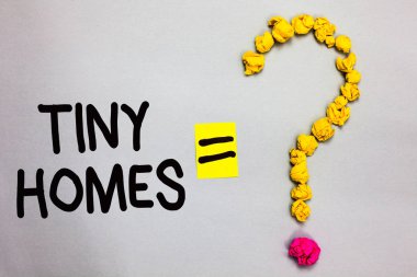 Kavramsal el Tiny evleri gösterilen yazma. İş fotoğraf vitrine evler sadece bir oda ya da iki içeren ve küçük ucuz soru işareti eşittir işareti beyaz arka plan oluşturan buruşuk giriş