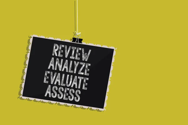 Handwriting text Review Analyze Evaluate Assess. Concept meaning Evaluation of performance feedback process Hanging blackboard message communication information sign yellow background