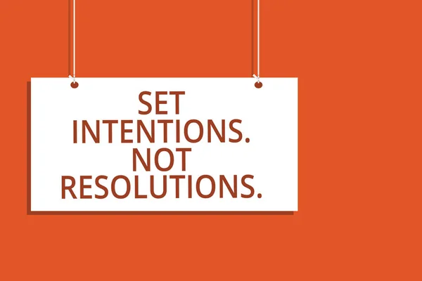 Word writing text Set Intentions. Not Resolutions.. Business concept for Positive choices for new start achieve goals Hanging board message communication open close sign orange background