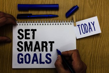 El yazısı metin akıllı gol ayarla. Ağımdaki ulaşılabilir hedefleri yapmak iyi iş anlam kavramı marker defter clothespin hatırlatma ahşap masa fincan kahve tutan adam planları