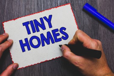 Tiny evleri gösterilen Not yazma. Sadece bir oda ya da iki iş fotoğraf vitrine evleri içeren ve küçük giriş ucuz kağıt kırmızı kenarlıklar işaret tutan adam hızlı fikirler ahşap arka plan