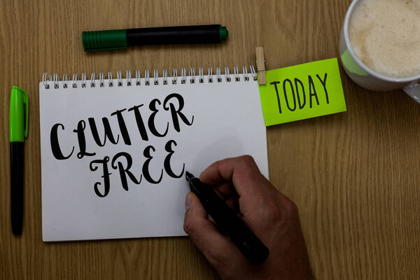 Writing note showing Clutter Free. Business photo showcasing Well organized and arranged Tidy All things in right places Man holding marker notebook clothepin reminder wooden table cup coffee