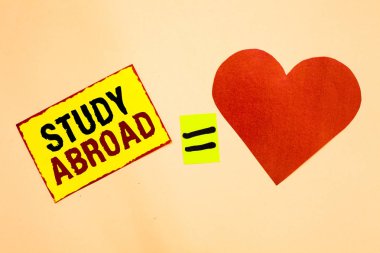 Handwriting text writing Study Abroad. Concept meaning Pursuing educational opportunities in a foreign country Yellow piece paper reminder equal sign red heart sending romantic feelings. clipart