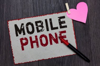 Cep telefonu gösterilen metin işareti. Kavramsal fotoğraf göndermek için kullanılan elde taşınır bir aygıtta almak aramaları ve mesajları beyaz sayfa kırmızı kenarlıklar marker clothespin kağıt kalp ahşap arka plan tutar.