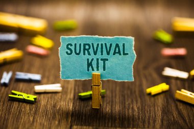 Word metin yazma Survival Kit. Acil ekipman biri mavi kağıt Not uyarı mektubu clothespins ahşap zemin tutan Clothespin yardımcı olmak koleksiyon öğeleri için iş kavramı.