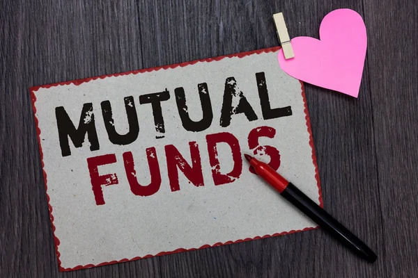 Text sign showing Mutual Funds. Conceptual photo An investment program funded by shareholders Individual Stocks White page red borders marker clothespin holds paper heart wood background.