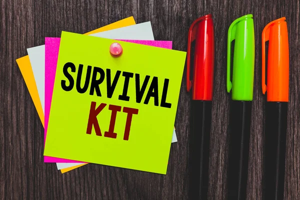 Conceptual hand writing showing Survival Kit. Business photo showcasing Emergency Equipment Collection of items to help someone Paper notes Communicate ideas Markers Wooden background.