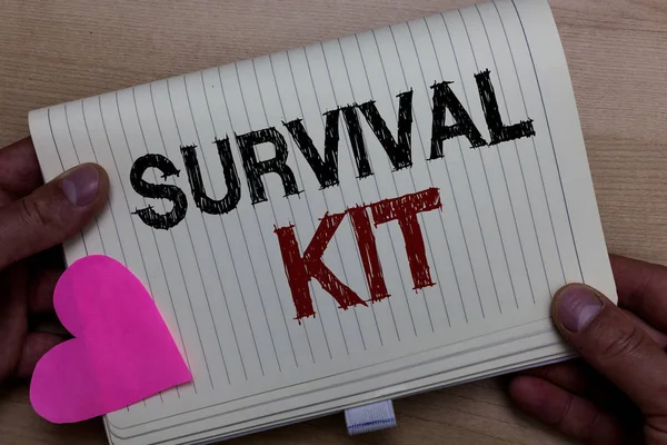 Word writing text Survival Kit. Business concept for Emergency Equipment Collection of items to help someone Man holding notebook paper heart Romantic ideas messages Wooden background.