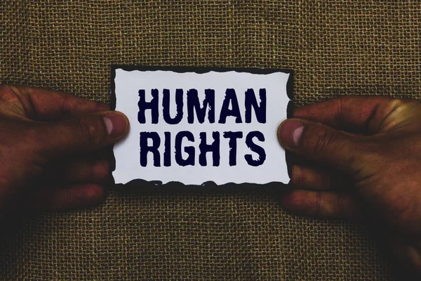 Handwriting text Human Rights. Concept meaning Moral Principles Standards Norms of a people protected by Law Man holding piece paper black borders jute background Communicate ideas. — Stock Photo, Image