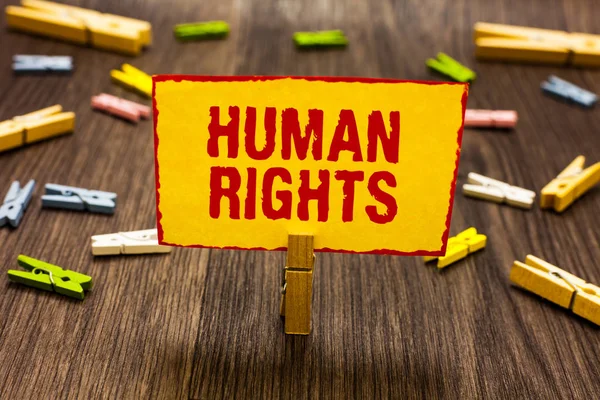 Text sign showing Human Rights. Conceptual photo Moral Principles Standards Norms of a people protected by Law Clothespin holding yellow paper note several clothespins wooden floor. — Stock Photo, Image