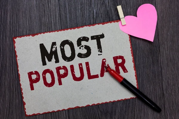 Text sign showing Most Popular. Conceptual photo Liked Followed Enjoyed by majority of the people in a society White page red borders marker clothespin holds paper heart wood background.