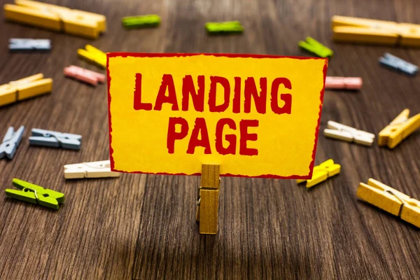 Text sign showing Landing Page. Conceptual photo Website accessed by clicking a link on another web page Clothespin holding yellow paper note several clothespins wooden floor. — Stock Photo, Image