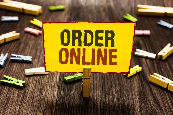 Handwriting text writing Order Online. Concept meaning Buying goods and services from the sellers over the internet Clothespin holding yellow paper note several clothespins wooden floor.