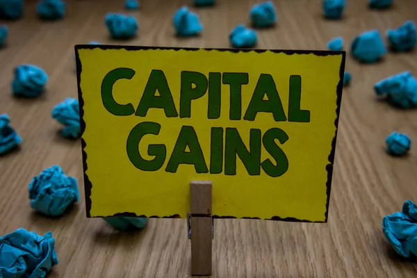 Text sign showing Capital Gains. Conceptual photo Bonds Shares Stocks Profit Income Tax Investment Funds Clothespin holding yellow paper note crumpled papers several tries mistakes.