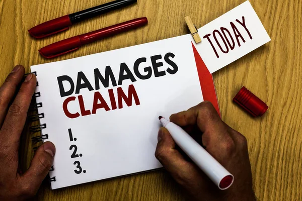 Handwriting text writing Damages Claim. Concept meaning Demand Compensation Litigate Insurance File Suit Man holding marker notebook clothespin reminder wooden table cup coffee. — Stock Photo, Image