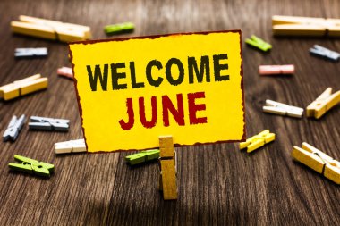 Hoş geldiniz Haziran yazma el yazısı metin. Takvim altıncı ay ikinci çeyrek otuz gün selamlar birkaç clothespins ahşap zemin sarı kağıt Not tutarak Clothespin anlam kavramı.