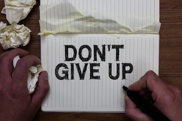 Writing note showing Don t not Give Up. Business photo showcasing Determined Persevering Continue to Believe in Yourself Man holding marker notebook crumpled papers ripped pages mistakes made.