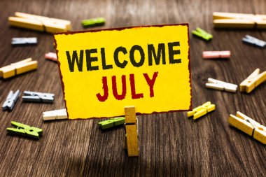 Hoş geldiniz Temmuz yazma el yazısı metin. Takvim yedinci ay 31days üçüncü çeyrek yeni sezon birkaç clothespins ahşap zemin sarı kağıt Not tutarak Clothespin anlam kavramı.