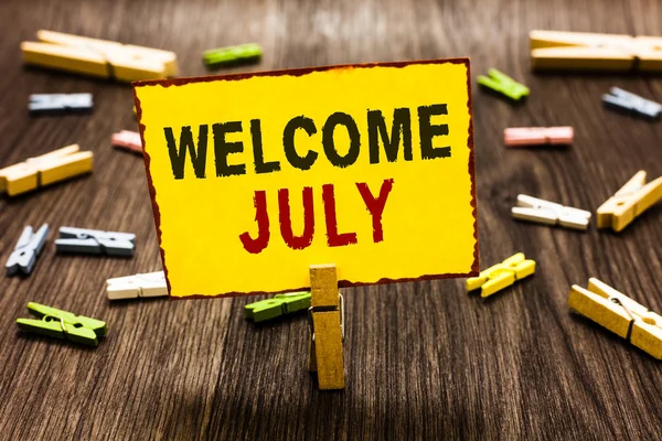 Hoş geldiniz Temmuz yazma el yazısı metin. Takvim yedinci ay 31days üçüncü çeyrek yeni sezon birkaç clothespins ahşap zemin sarı kağıt Not tutarak Clothespin anlam kavramı.